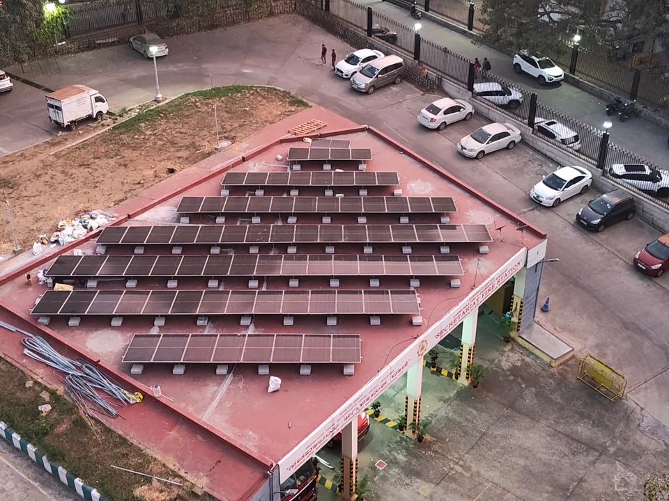 Aerial view at dusk of a long rooftop solar array covering the roof of a fire station.