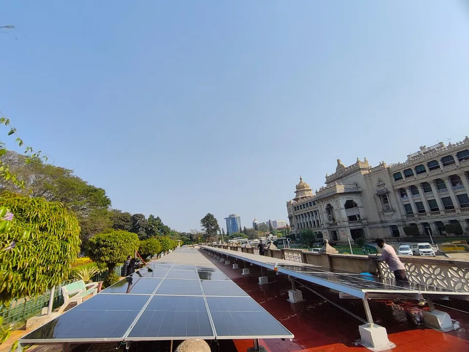 A cleaning crew washing rooftop solar modules on the Vidhana Soudha terrace